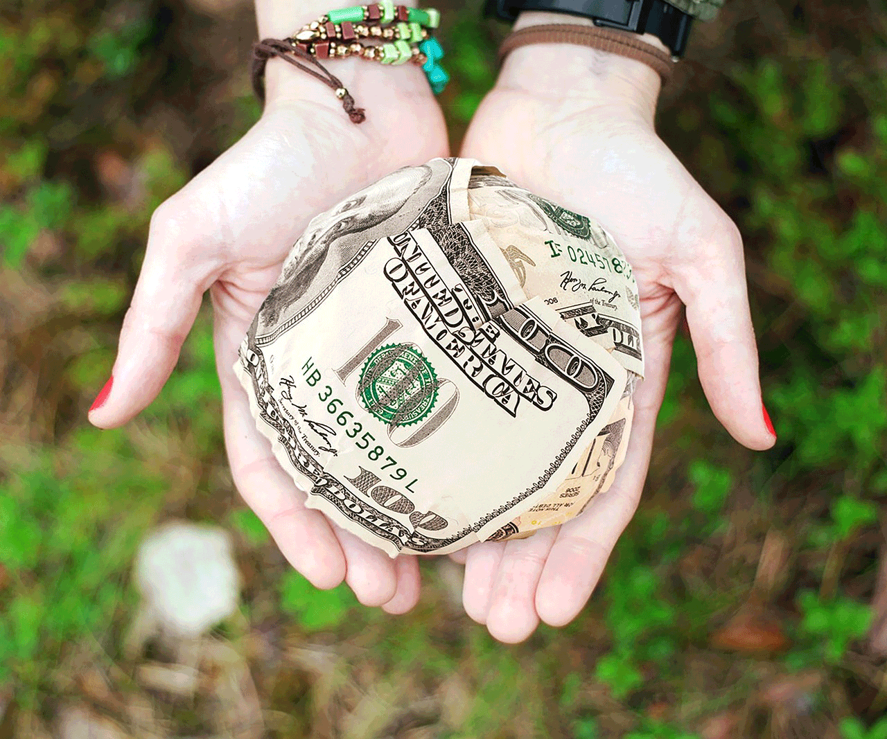 hands holding 100 dollar bill money ball