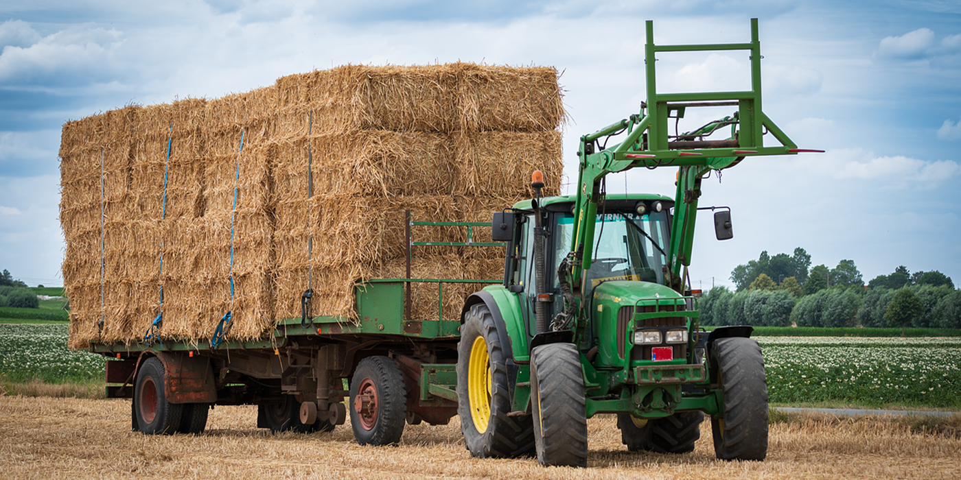 Green Tractor with trailer full of hay bales 